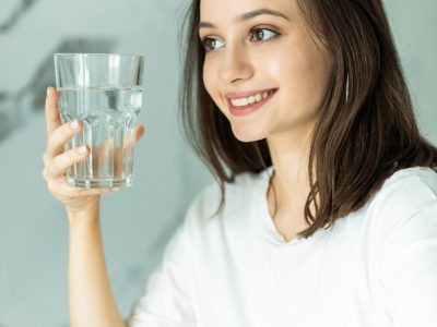 Beautiful young woman holds a glass with water on kitchen